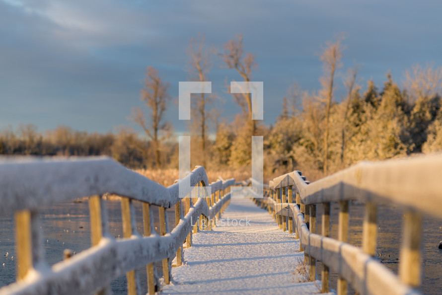 snow on a railing of a wood bridge 