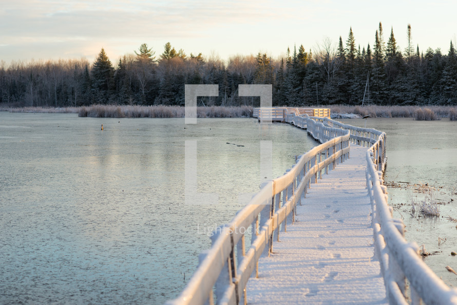 snow on a bridge over a lake 