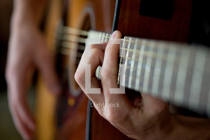 hands on the strings of a guitar 