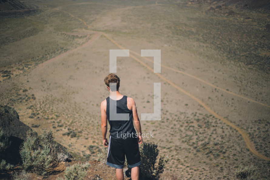 Boy walking on a dirt road.