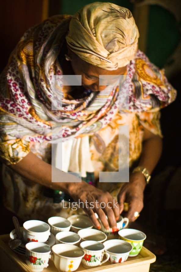 A woman in Ethiopia arranging tea cups 