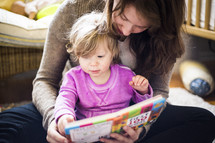 mother and toddler daughter reading together 