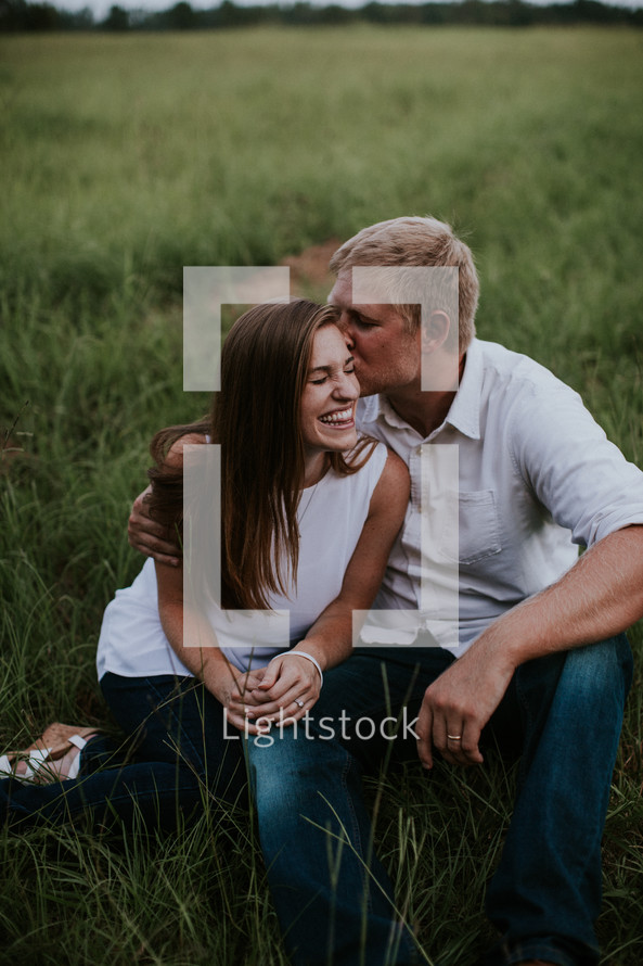 couple sitting in grass snuggling 