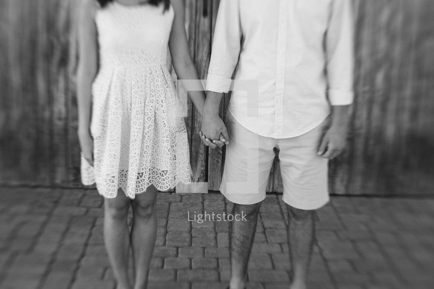 Couple holding hands standing outside.