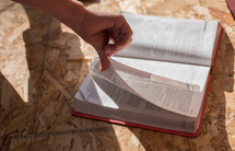 person turning pages of a Bible 