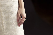 Bride's hand on wedding gown with a simple black background