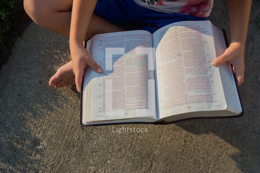 child reading a Bible outdoors 