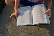 child reading a Bible outdoors 