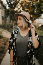 Pretty woman in hat standing outside