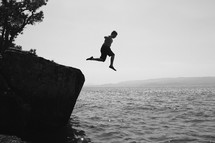 man jumping into ocean water 
