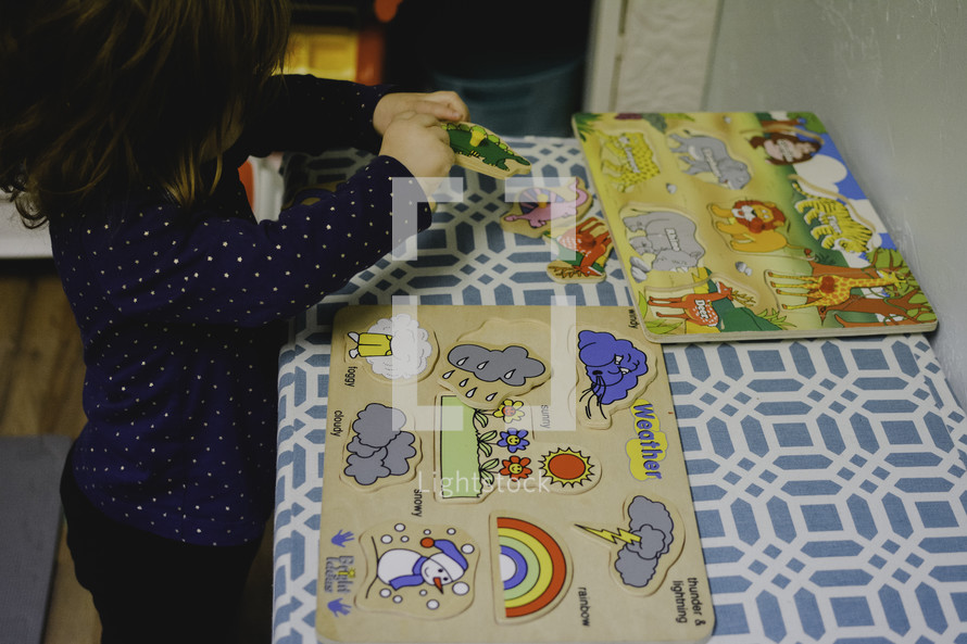 a toddler girl building a puzzle 