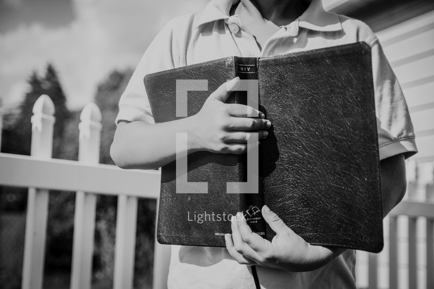 a boy holding a Bible close to his chest 