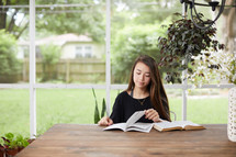 a young woman reading a Bible on her porch 