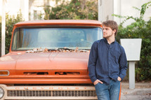 a man with a beard standing in front of an old truck 
