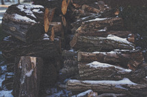 snow on a pile of firewood 