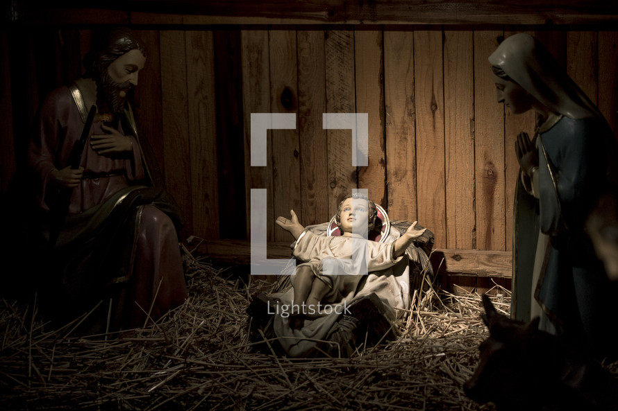 Mary and Joseph gazing upon baby Jesus in manger in nativity scene.