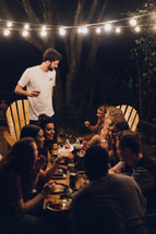 friends gathered around a table talking at a dinner party 