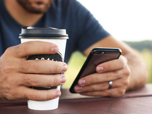 man holding a to go coffee cup and cellphone 