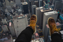 feet dangling over a city below 