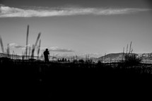 silhouette of a man standing in a field surrounded by mountains 
