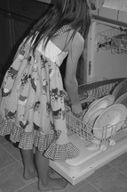 a little girl loading the dishwasher 