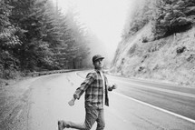 a man in a ball cap dancing on the side of a road 