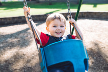 a toddler boy on a swing set 