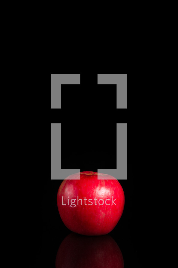 A red apple set against a black background.