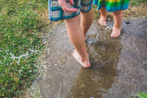 kids playing in a puddle in their barefeet