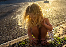 girl child squatting outdoors on a summer day 