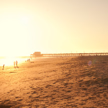 a long fishing pier on a beach at sunset