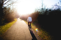 man riding a bicycle on a sunny path 