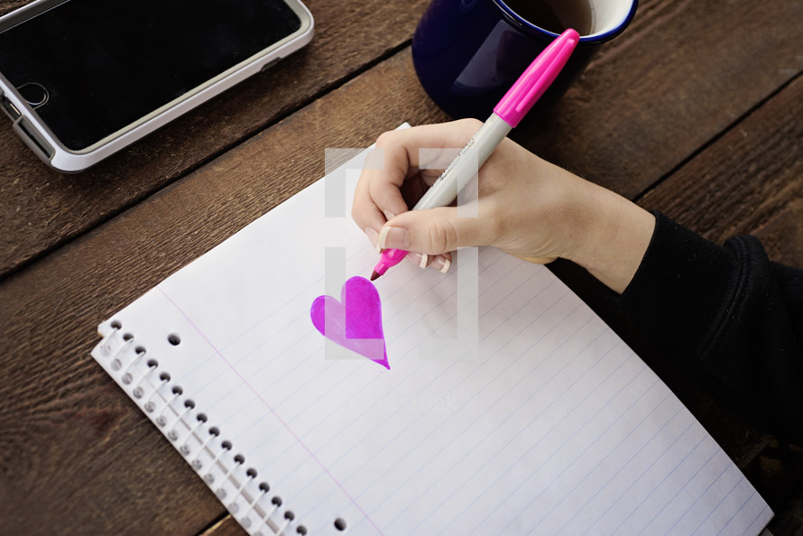 girl drawing a pink heart on paper 
