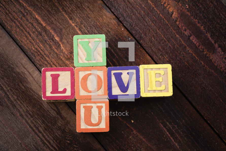 "Love You" spelled out with children's colorful wooden blocks.