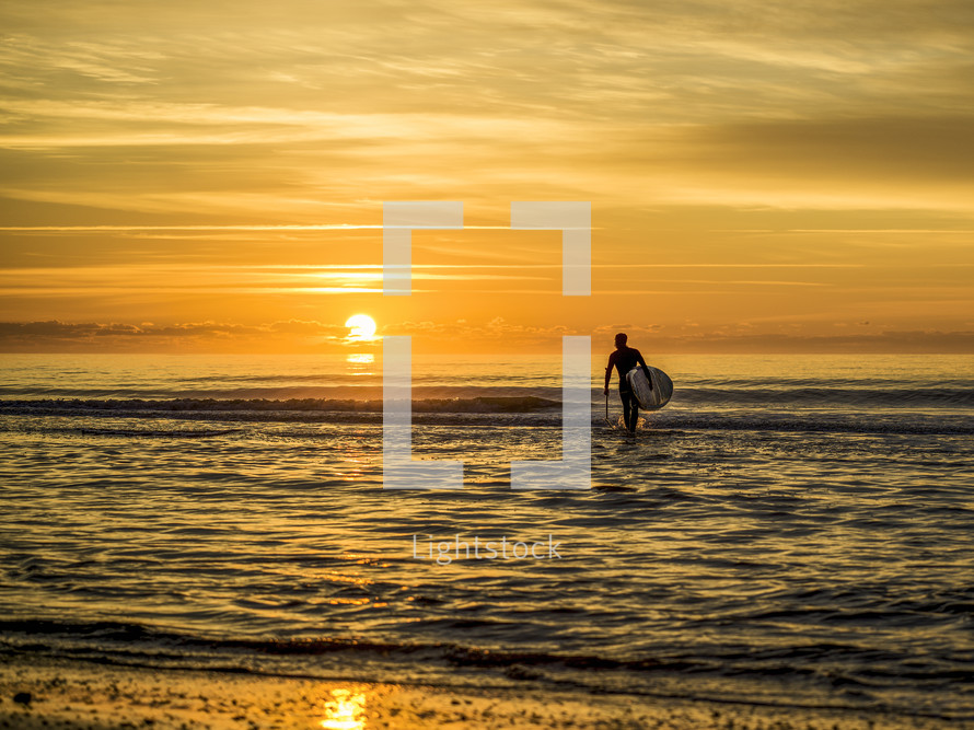 a surfer on a beach at sunset 