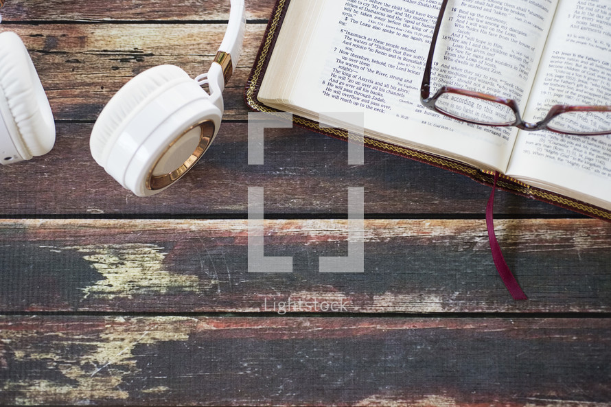 reading glasses on an open Bible and headphones 