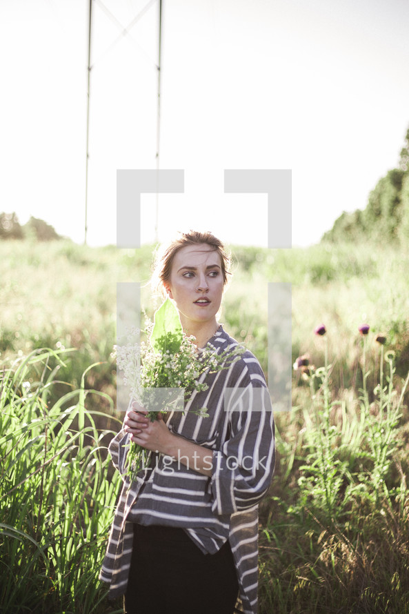a woman holding picked flowers in a field 