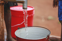 water from a spigot falling into a bucket 