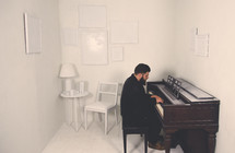 a man playing a piano in a white room 
