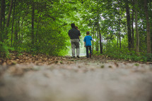 father and sons walking on a path through the woods 