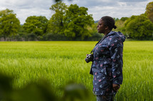 a woman with a camera standing in a field 