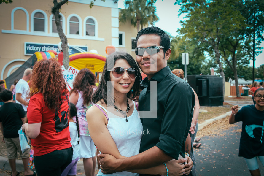 A couple with arms around each other at an outdoor festival.