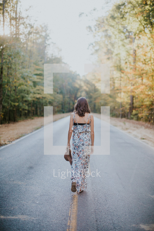 young woman walking down the center of a road 