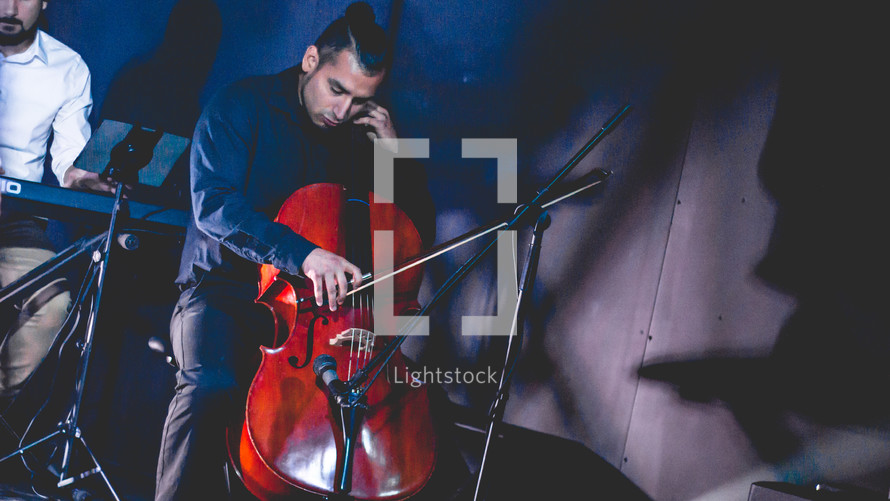 a man on stage playing a cello 