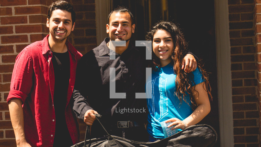 friends standing together holding a guitar case 