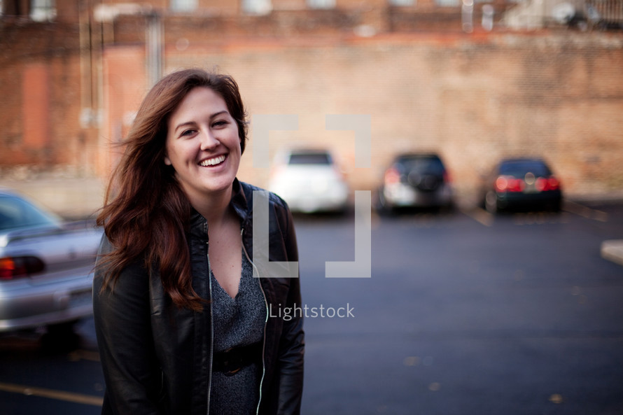 a smiling woman standing in a parking lot 