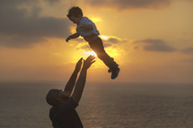 a father lifting his son into the air 