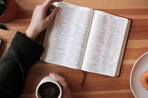 a woman reading a Bible and coffee and donuts 