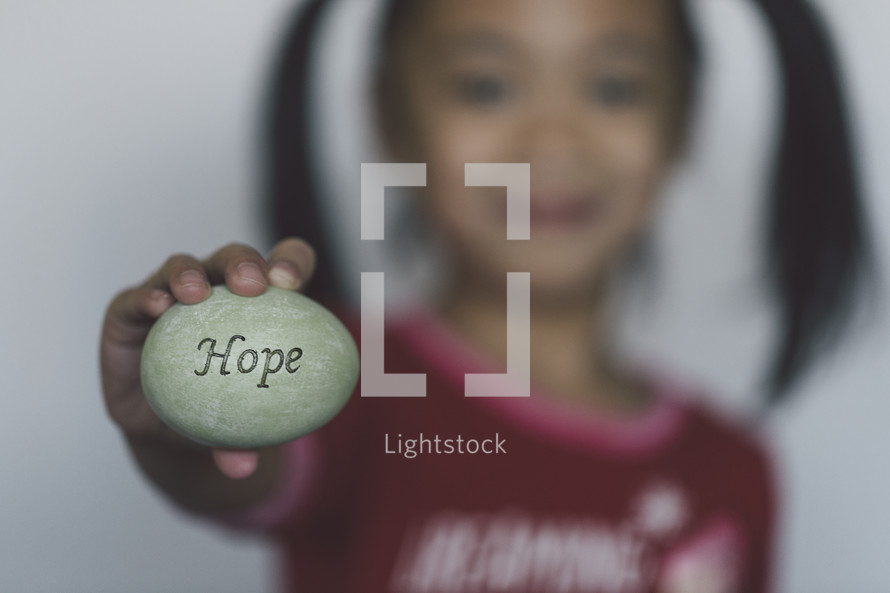 girl holding an Easter egg stamped with the word Hope 