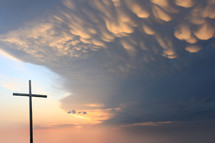 cross against a sky with dramatic clouds at sunset 